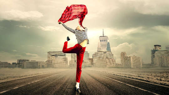 Having the Courage to Be True to Ourselves woman dancing in the middle of an empty highway with a city skyline in the background